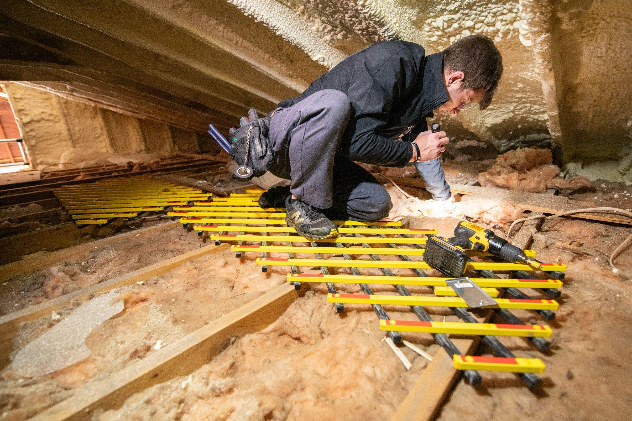 A technician inspects attic insulation to help improve home comfort with attic insulation services in Fresno.