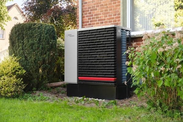 Outdoor heat pump unit installed by residential heating services in Central Valley beside a brick home to provide energy-efficient residential heating and cooling.