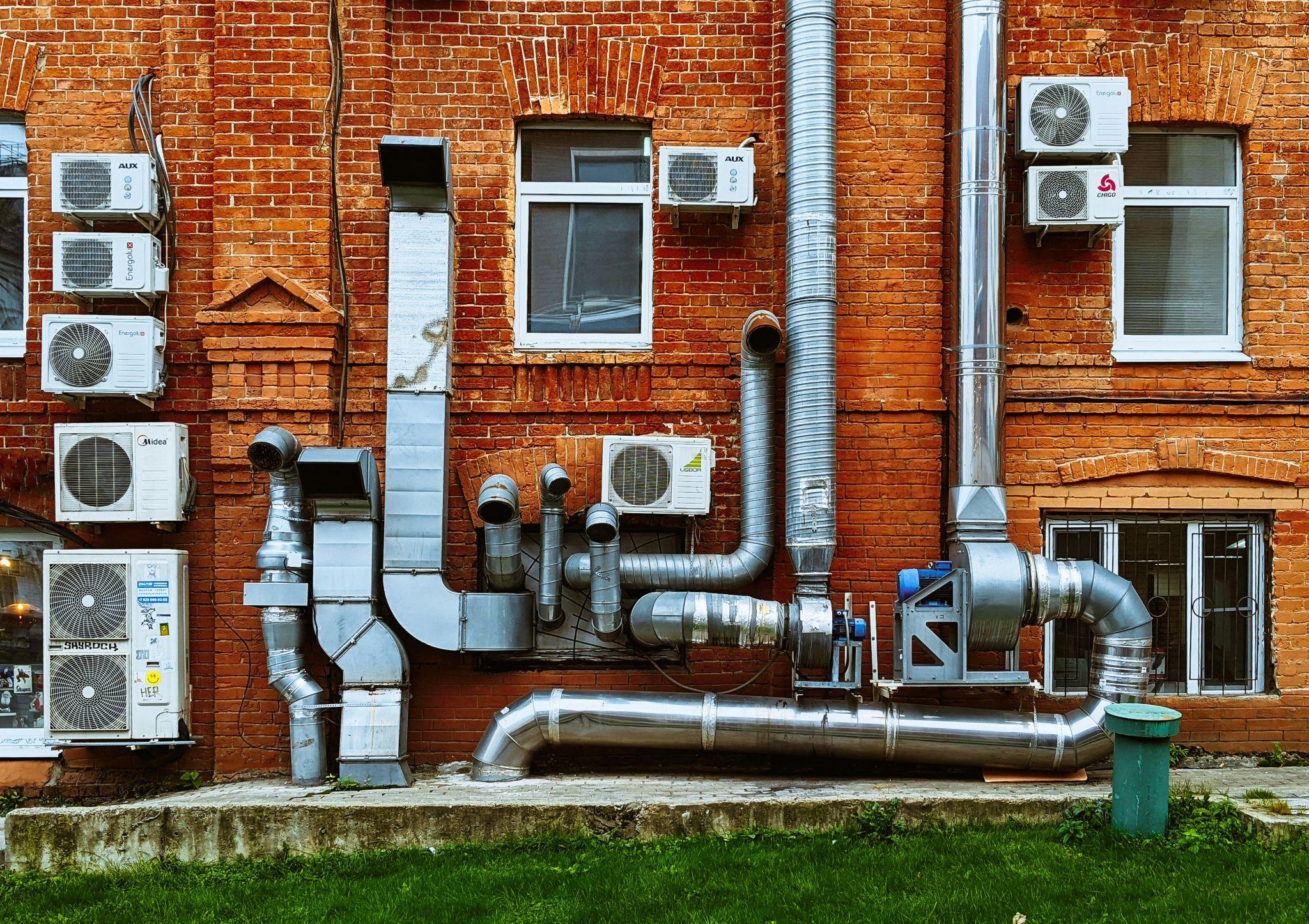 Commercial air conditioning units, metal ducts, and ventilation systems on a building showcase commercial air conditioning services in Fresno.